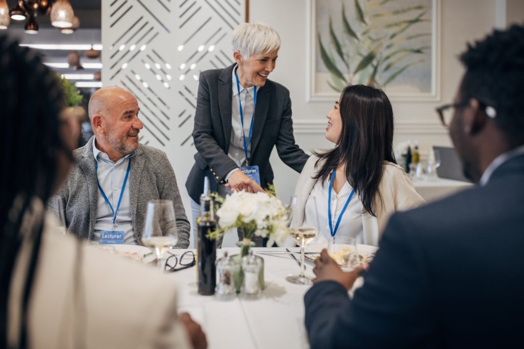 Group of women and men at reception social with wine and food - seated at table