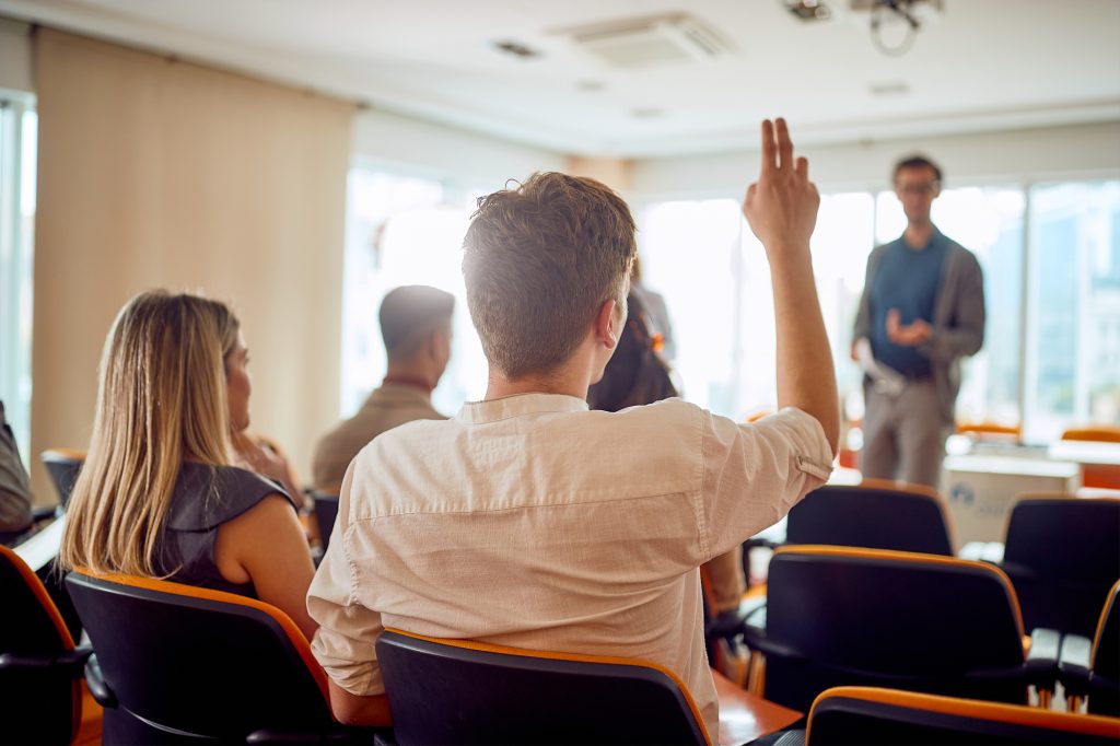 A young businessman asks a question during a business lecture in a working atmosphere in the conference room. Business, people, company
