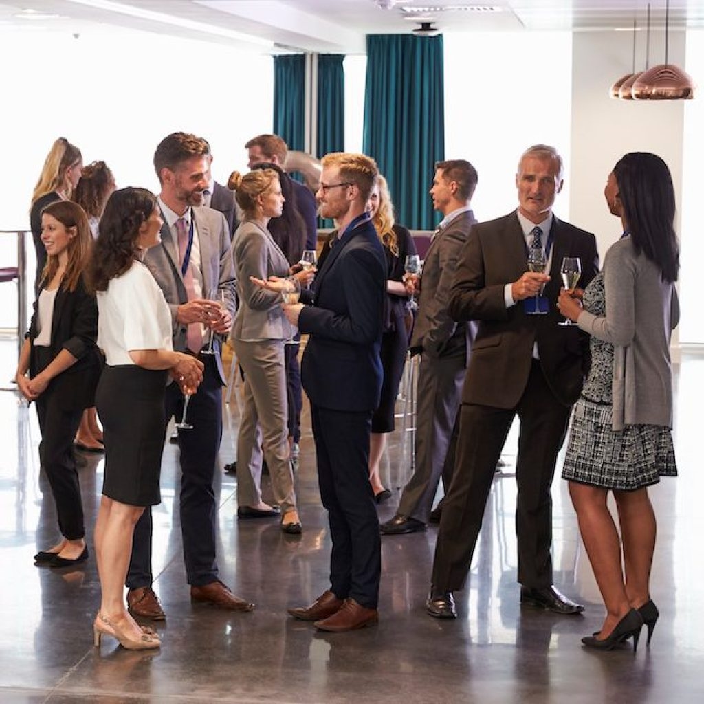 Group of young people standing and talking at social event during conference